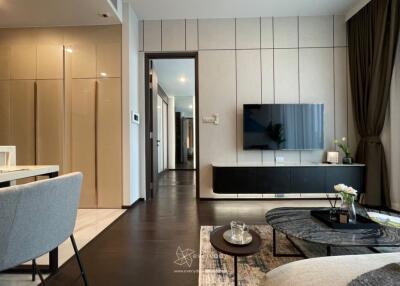 Modern living room with a wall-mounted TV, coffee table, and an open view into the hallway and other rooms