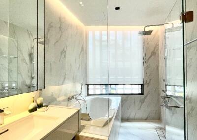 Modern bathroom with marble tiles, a glass shower, and a bathtub