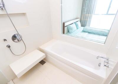 Modern bathroom with a bathtub, shower, and view into the bedroom