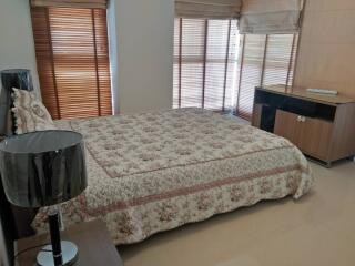 Well-lit bedroom with large windows and floral bedspread