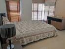 Well-lit bedroom with large windows and floral bedspread