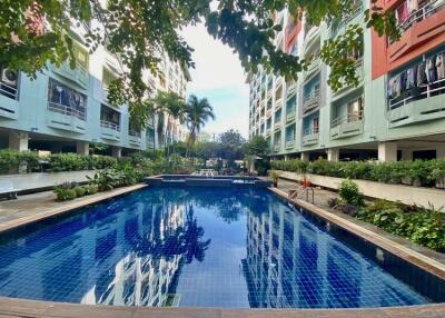 Swimming pool in a residential complex with surrounding greenery and buildings