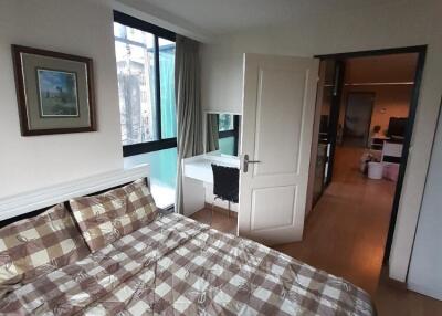 Spacious bedroom with a checkered bedspread and a window view.