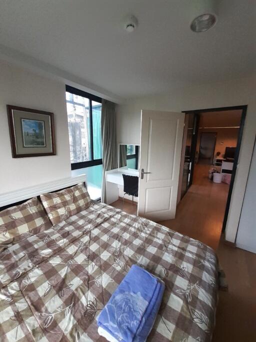 Spacious bedroom with a checkered bedspread and a window view.