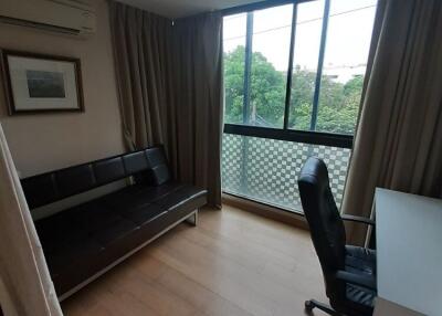 A bedroom with a desk and chair, sofa bed, and large window