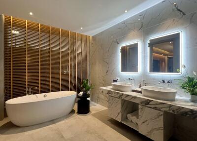 Modern bathroom with double vanity, bathtub, and accent lighting