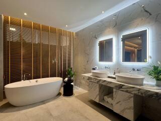 Modern bathroom with double vanity, bathtub, and accent lighting