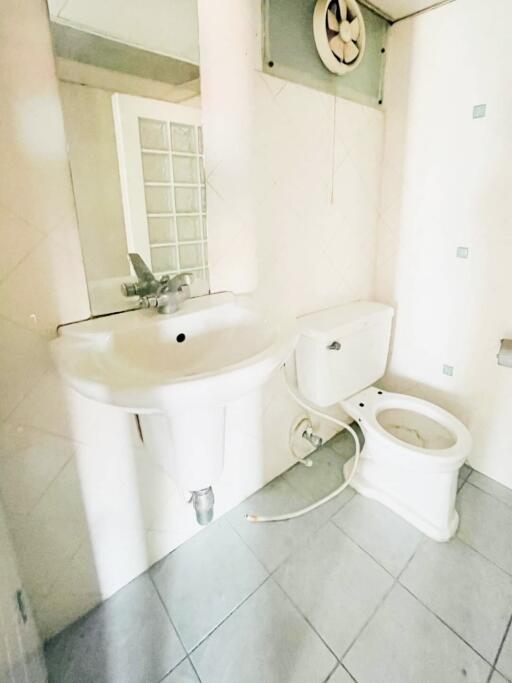 White bathroom with sink, toilet, and wall-mounted fan