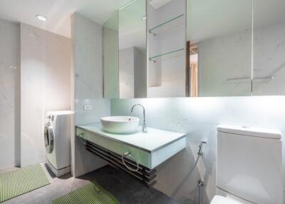 Modern bathroom with sink, mirror, toilet, and washing machine