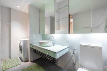 Modern bathroom with sink, mirror, toilet, and washing machine