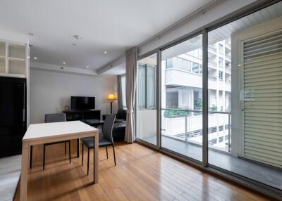 Modern living area with dining table, chairs, TV, and large windows overlooking a balcony