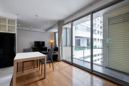 Modern living area with dining table, chairs, TV, and large windows overlooking a balcony