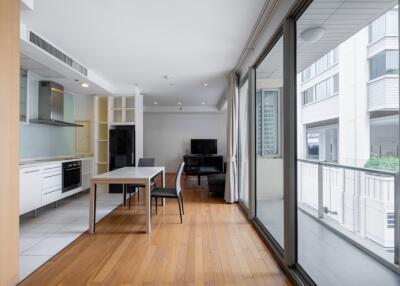 Modern living area with dining table, kitchen, and large glass windows