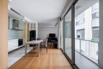 Modern living area with dining table, kitchen, and large glass windows