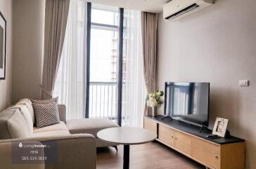 Cozy living room with a sofa, TV, and large window