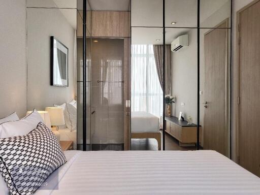 Modern bedroom with mirrored wardrobe doors, bed, checkered cushions, and ambient lighting