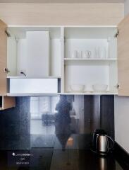 Modern kitchen with open cupboards showing crockery and a kettle on the countertop