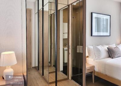 Modern bedroom with mirrored closet, bed, and nightstand with a lamp