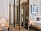 Modern bedroom with mirrored closet, bed, and nightstand with a lamp