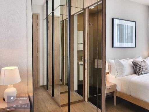 Modern bedroom with mirrored closet, bed, and nightstand with a lamp