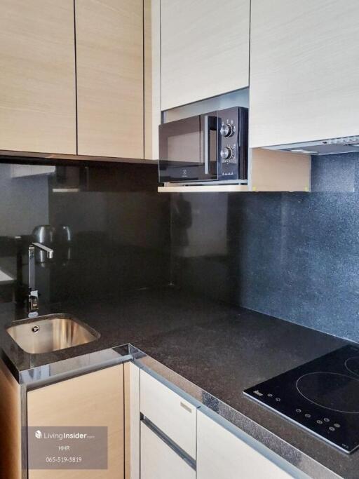 Modern kitchen with black countertop, sink, microwave, and stovetop