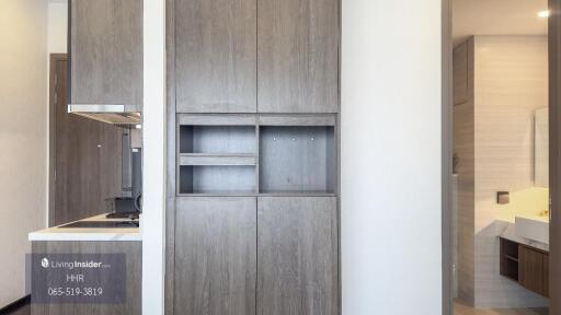 Modern kitchen with wooden cabinets and visible bathroom entrance