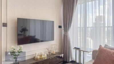 Modern living room with a wall-mounted TV and a large window with sheer curtains