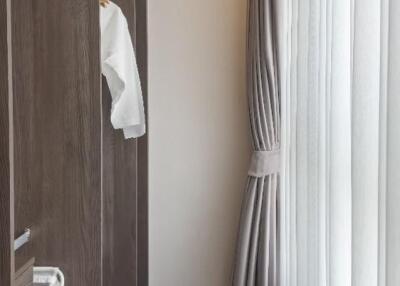 walk-in closet with dark wood shelving and white curtains