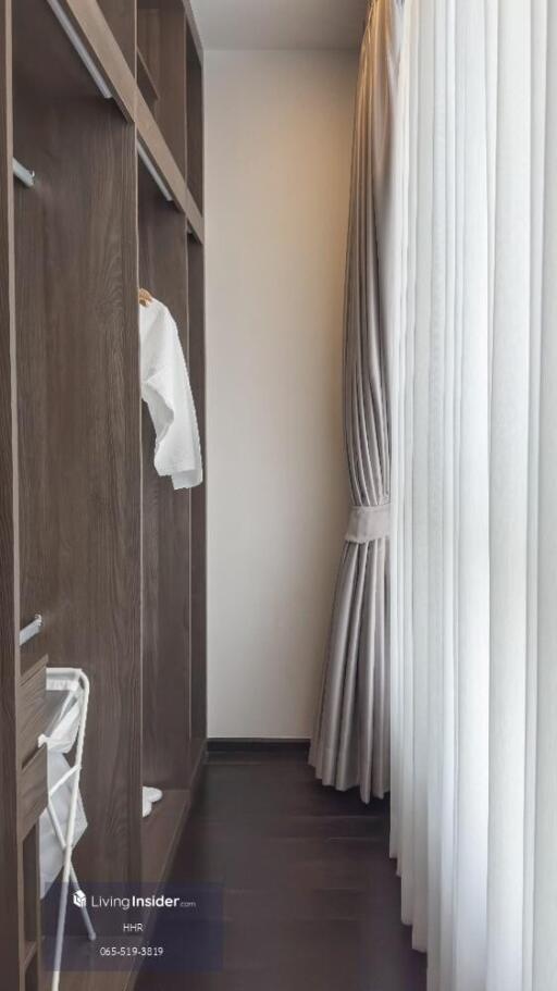 walk-in closet with dark wood shelving and white curtains