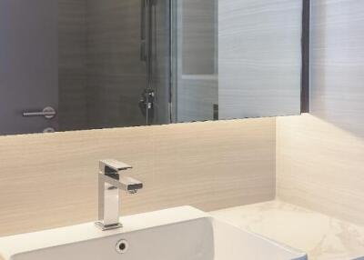 A modern bathroom sink with a large mirror and countertop.