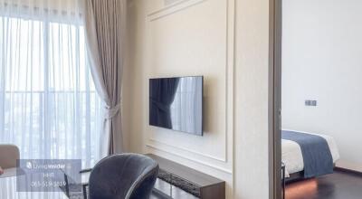 Living area with a wall-mounted TV and a view into the bedroom