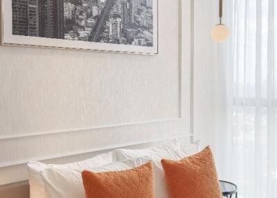 A modern bedroom with cityscape artwork above the bed and orange pillows