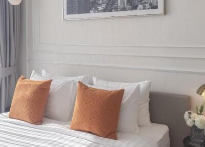 Bedroom with decor and bed made with white linens and orange accent pillows