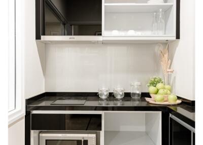 Modern kitchen with black and white cabinets, stove, microwave, and shelves