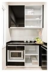 Modern kitchen with black and white cabinets, stove, microwave, and shelves