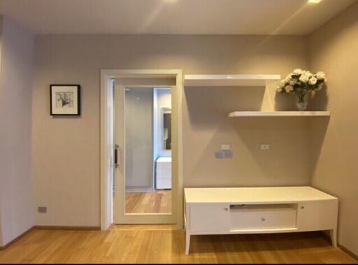 Living room with wooden floor, wall mounted shelves, and a framed picture