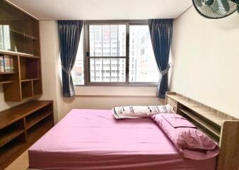 Bedroom with pink bed, shelves, and large window