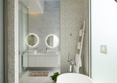 Modern bathroom with a white bathtub, double mirrors, and elegant decor