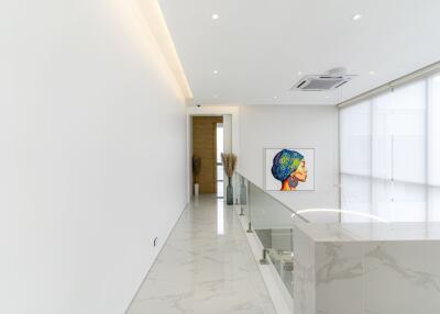 Modern hallway in a luxury home with a marble floor, artwork, and glass balcony