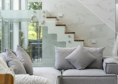 Modern living room with grey couch and glass stair railing