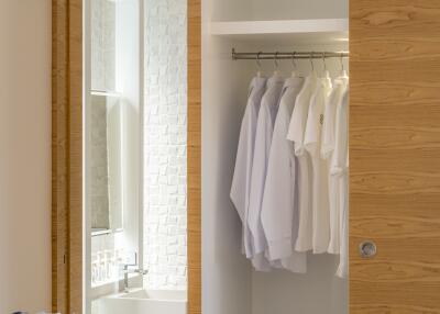 Modern wardrobe with neatly arranged shirts and an adjacent bathroom