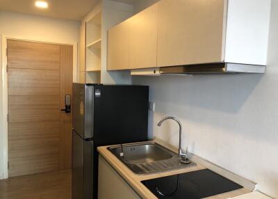 Modern kitchen with wooden cabinetry, sink, refrigerator, and electric stove