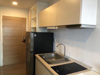 Modern kitchen with wooden cabinetry, sink, refrigerator, and electric stove