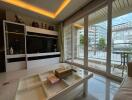 Modern living room with a large TV, decorative shelving, and floor-to-ceiling windows