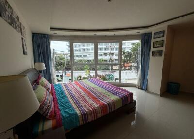 Bedroom with large windows and a colorful striped bedspread