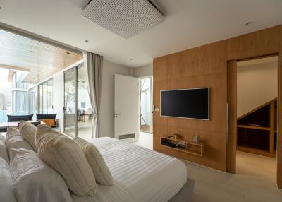 Modern bedroom with large windows, wall-mounted TV, and a view to the outdoors