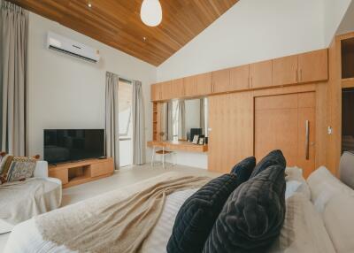 Spacious bedroom with wooden ceiling, large wardrobe, and modern amenities