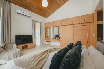 Spacious bedroom with wooden ceiling, large wardrobe, and modern amenities