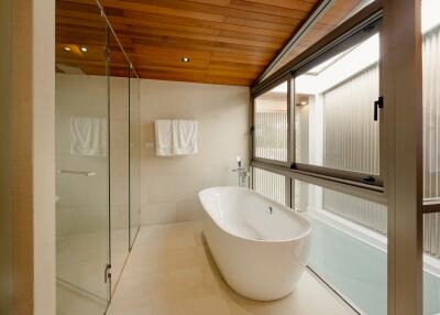 Modern bathroom with large window, standalone tub, and glass-enclosed shower