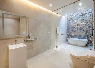 Modern bathroom with glass shower and stone accent wall